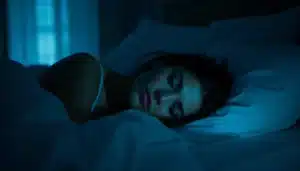 Femme éveillée dans l'obscurité regardant un réveil affichant 02h02, en lien avec la signification spirituelle de cette heure miroir pour les flammes jumelles