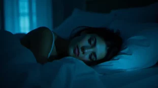 Femme éveillée dans l'obscurité regardant un réveil affichant 02h02, en lien avec la signification spirituelle de cette heure miroir pour les flammes jumelles