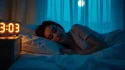 Femme éveillée dans la nuit regardant l'heure 03h03 sur son réveil, main posée sur le cœur, symbolisant la signification amour du miroir horaire