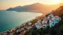 Vue aérienne panoramique de la ville de Béjaïa au coucher du soleil, avec la mer Méditerranée et les montagnes kabyles en arrière-plan, illustrant l'énergie ancestrale et spirituelle d'une naissance à Béjaïa